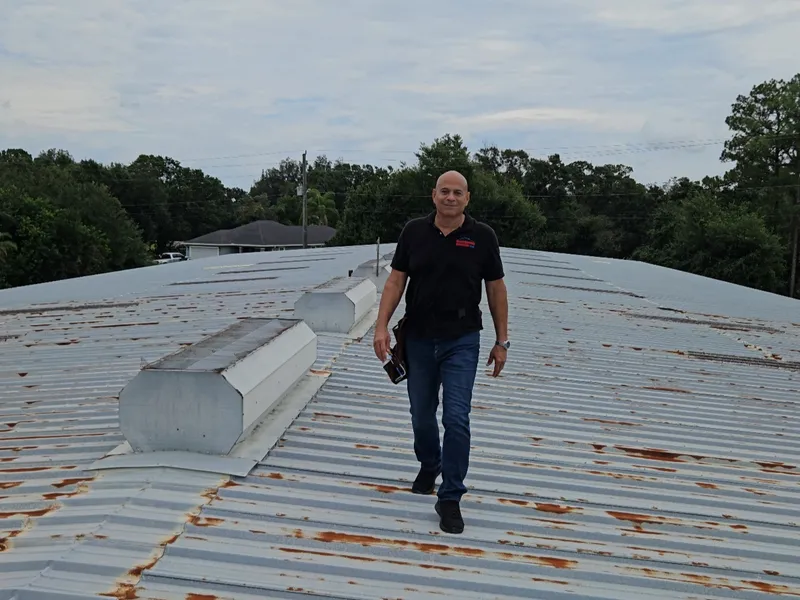 Ron inspecting a weathered metal roof on a Florida job site